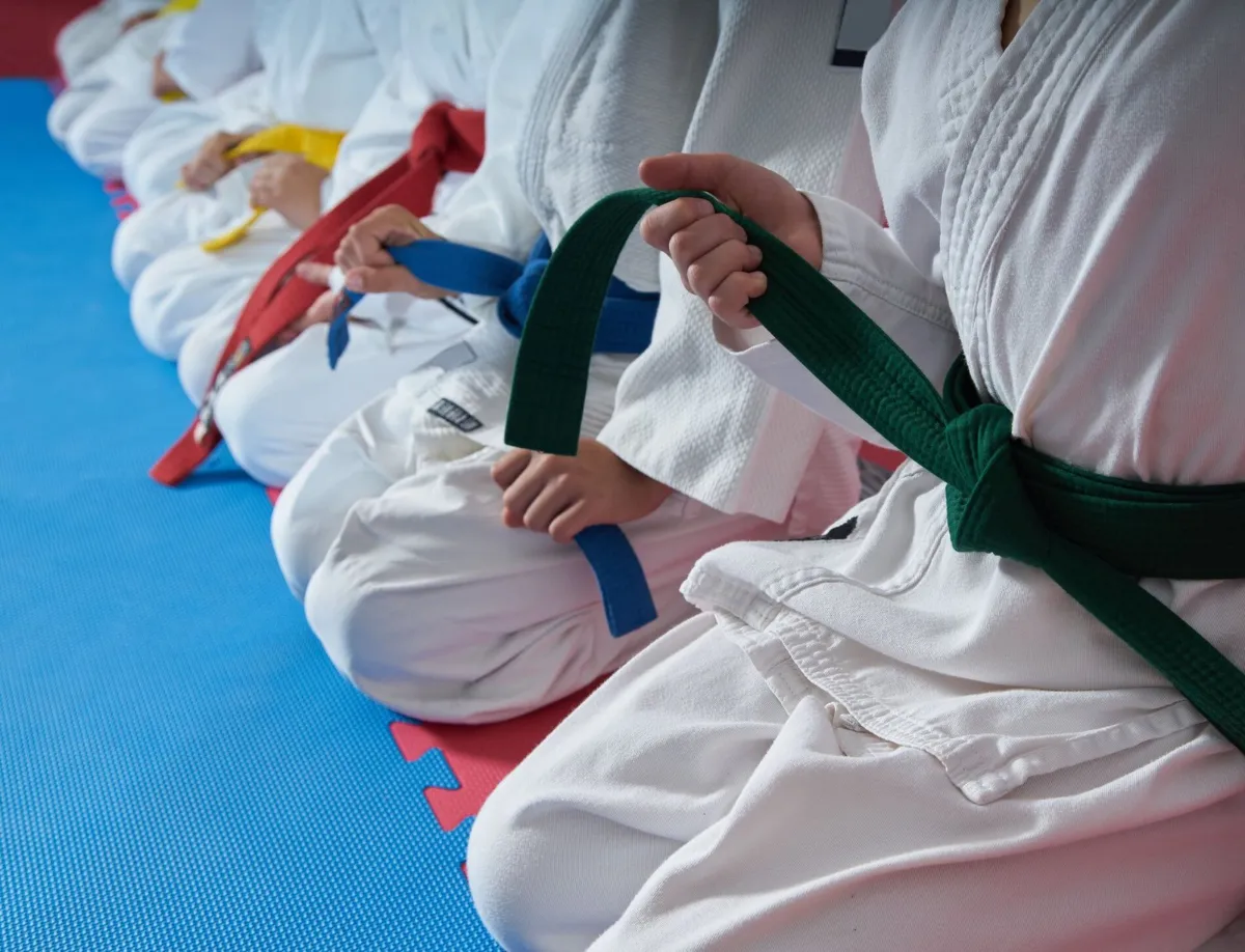 Children in martial arts uniforms holding their colored belts