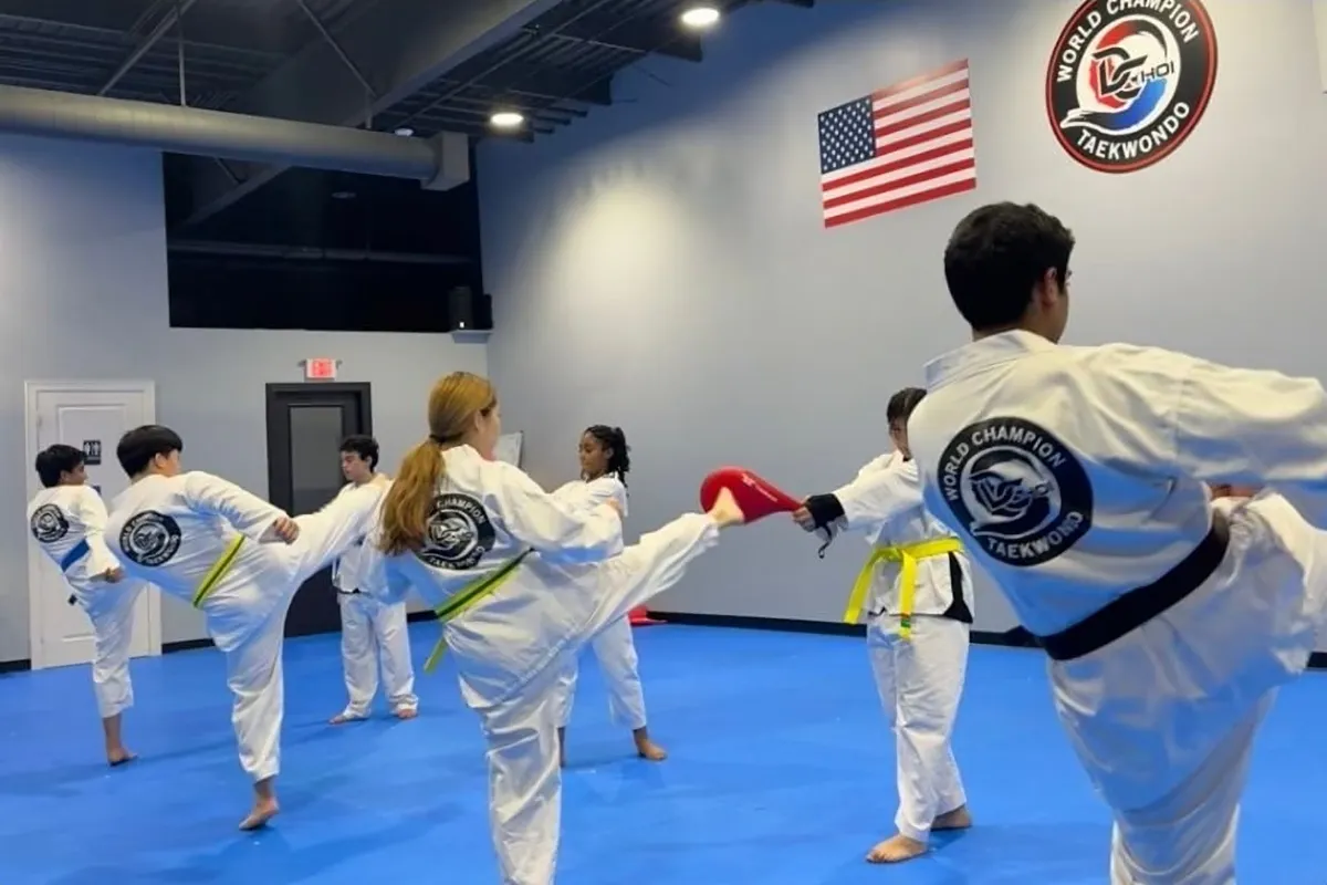 Teen and adult students practicing kicks in class