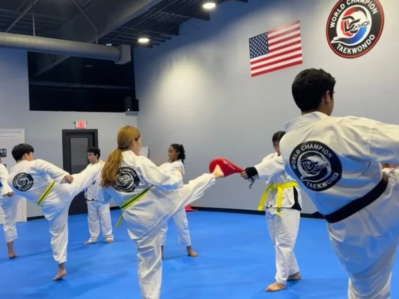Teen and adult students practicing kicks in class